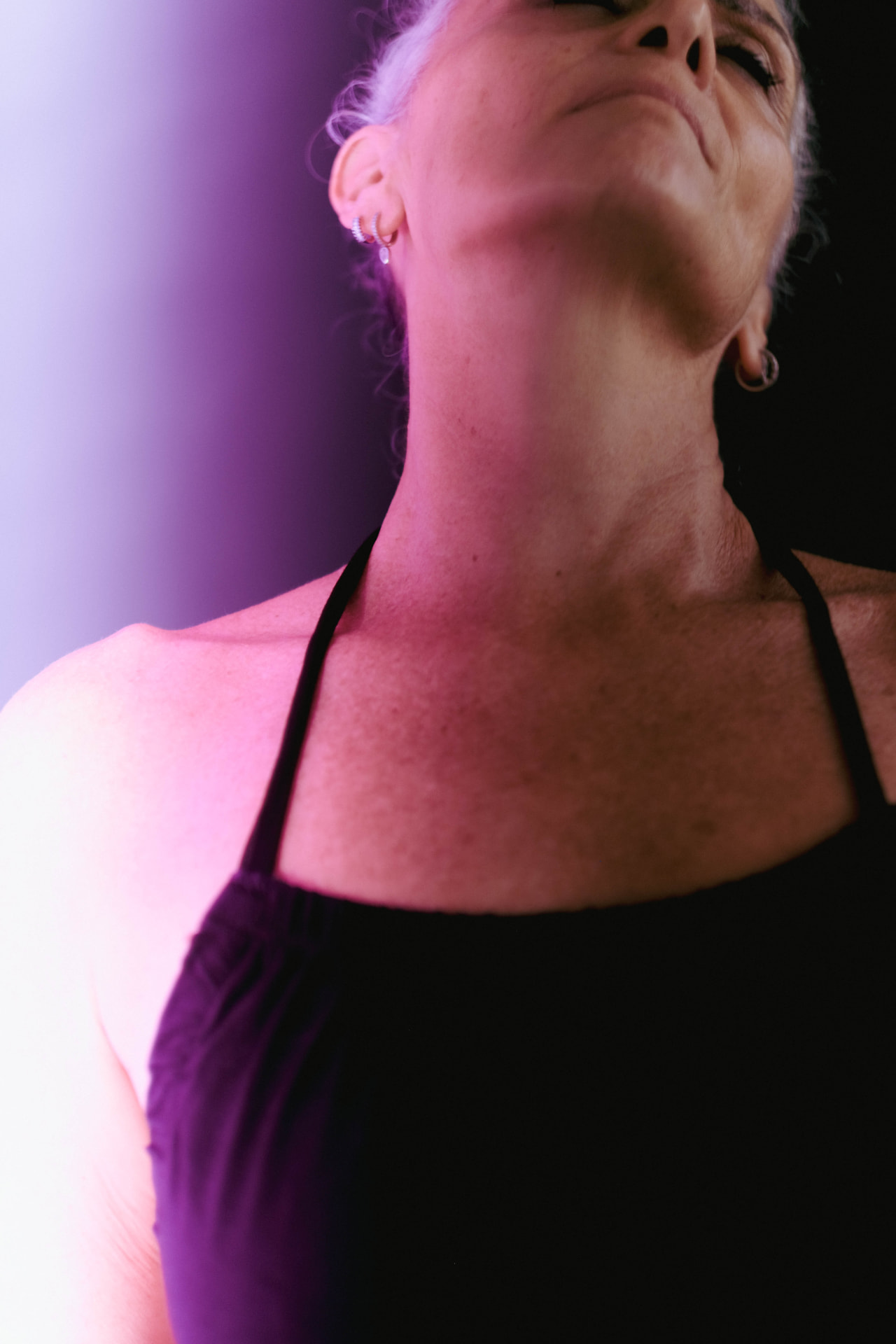 Emmanuelle, head tilted back in violet light
